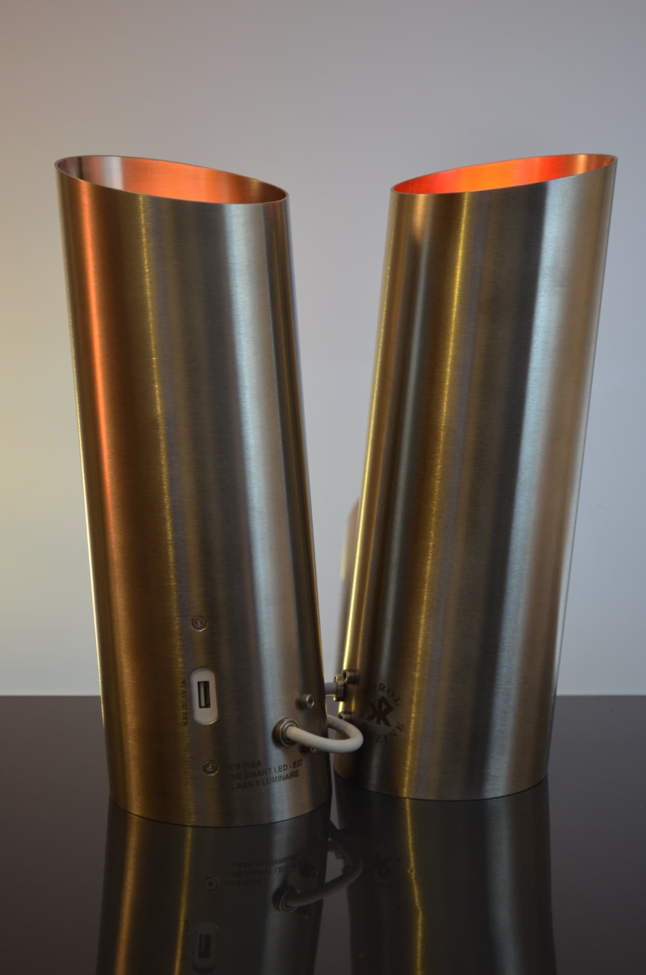 Two Pisa brushed stainless steel luminaires with copper-glowing interiors